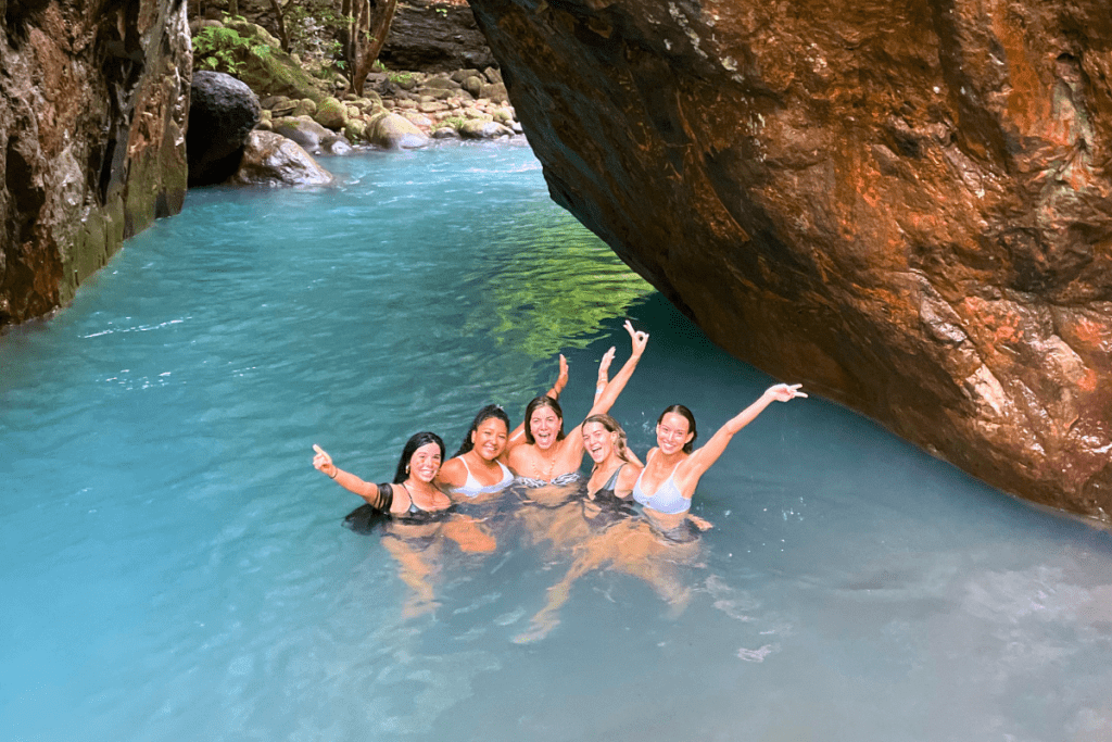 Women posing before a cavern in La Leona Waterfall Adventure Hike in Costa Rica.